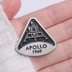 Spilla commemorativa Apollo 1969 con dettaglio della navicella spaziale e la scritta "APOLLO 1969" in rilievo, perfetta come decorazione o collezione.
