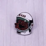 Pulsante in metallo con casco spaziale e volto di cane, decorato con la scritta "CCCP" in rosso, simbolo di un'epoca storica e di un movimento culturale sovietico.