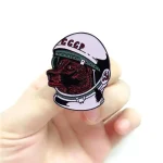 Perno di metallo con disegno di cane e casco spaziale, simbolo di esplorazione e avventura scientifica.