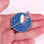 Spilla a forma di satellite e stella, ispirata all'esplorazione spaziale, perfetta come accessorio di moda o decorazione scientifica.