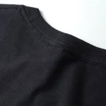 Dettaglio di una maglietta nera con cuciture sottili, tessuto morbido e di alta qualità, perfetta per un look casual e comodo.