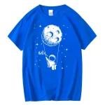 Maglietta blu con grafica di un astronauta che si aggrappa a una luna, con stelle e la scritta "Hello". Perfetta per gli appassionati di spazio e decorazioni scientifiche.