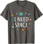T-shirt grigia con stampa "I NEED SPACE" e disegni di pianeti, astronavi e stelle, perfetta per appassionati di spazio e scienza.