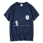 Maglietta blu con stampa di un astronauta che gioca a golf nello spazio, con galassia e stelle sullo sfondo, perfetta per appassionati di scienza e astronomia.