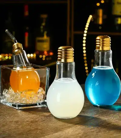 Tre lampadine scientifiche colorate come decorazioni da tavolo, con filamenti visibili e base in metallo, ideali per arredamento a tema scientifico o decorazioni creative.