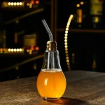 Lampadina decorativa trasformata in bicchiere con succo, perfetta come oggetto decorativo o regalo a tema scientifico.