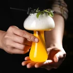Vaso di cocktail con decorazioni verdi e schiuma, presentato come oggetto decorativo scientifico originale. Perfetto per appassionati di scienza e design innovativo.