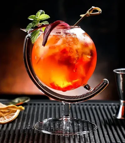 Cocktail colorato in bicchiere di vetro con frutta, menta e cannuccia, perfetto come decorazione scientifica o oggetto da collezione.