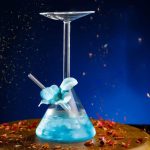 Vaso di laboratorio con liquido blu e pipetta, simbolo di scienza e ricerca, posizionato su una superficie decorata con petali di fiori, con sfondo scuro e effetti di luce.