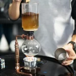 Distillatore scientifico con liquido color ambra in fase di distillazione.