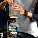 Persona che esegue un esperimento chimico con becher e apparecchiature di laboratorio, evidenziando l'attività scientifica e la curiosità.