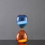 Orologio a clessidra con sabbia blu e arancione, simbolo di tempo e scienza, perfetto come decorazione scientifica per appassionati di chimica e fisica.