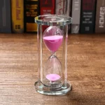Clessidra di vetro con sabbia rosa, oggetto decorativo scientifico, perfetta per decorazioni e studi di fisica.