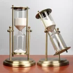 Orologio a clessidra decorativo con struttura in metallo dorato e vetro, perfetto come oggetto di arredamento scientifico o da collezione.