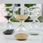 Orologio a sabbia decorativo in vetro con sabbia colorata, perfetto come oggetto scientifico e decorativo per ambienti moderni e studi.