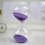 Sabbia viola in clessidra di vetro, decorazione scientifica elegante e originale.