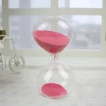 Orologio a clessidra decorativo con sabbia rosa, perfetto come oggetto scientifico e decorativo per ambienti moderni e studi.