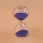 Clessidra con sabbia viola, simbolo di tempo e pazienza, perfetta come decorazione scientifica o da scrivania.