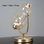 Vaso a clessidra decorativo con struttura in metallo dorato e vetro, perfetto come oggetto di arredamento scientifico o da collezione. Dimensioni: 16cm x 15cm x 31cm.