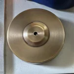 Piatto di metallo con superficie liscia e foro centrale, ideale come decorazione scientifica o oggetto da collezione. Perfetto per appassionati di scienza e design industriale.