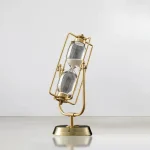 Orologio a clessidra decorativo con struttura in metallo dorato e vetro, perfetto come oggetto di decorazione scientifica o da scrivania.