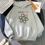 Maglione grigio con stampa di un atomo stilizzato e testo "Quantum Physics" in evidenza, ideale per appassionati di scienza e fisica.