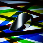 Mouse nero lucido posizionato su uno sfondo di strisce colorate, creando un contrasto moderno e dinamico. Perfetto come decorazione scientifica o elemento di design innovativo.