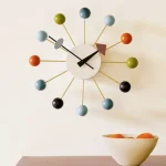 Orologio da parete con design moderno, sfere colorate e lancette nere, ideale come decorazione scientifica e originale per la casa o l'ufficio.