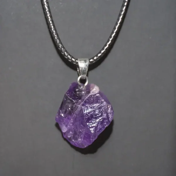 Pendente con cristallo di ametista naturale, gioiello decorativo e simbolico, sospeso su una catena metallica. Perfetto come regalo o accessorio di stile.