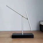 Scultura di Penrose in metallo con forma piramidale, simbolo di illusione ottica e matematica, su base nera, perfetta come decorazione scientifica moderna.