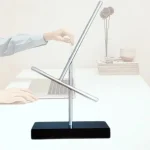 Modello di equilibrio dinamico con due sfere in metallo su supporto nero, simbolo di scienza e fisica.
