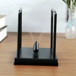 Modello di pendolo di Newton in miniatura con sfera in acciaio e supporti in metallo, ideale come decorazione scientifica o oggetto educativo da scrivania.