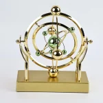 Oggetto decorativo a forma di modello atomico, realizzato in materiali metallici dorati e verdi, ideale come decorazione scientifica o da scrivania.