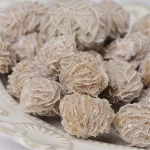 Palline di zenzero cristallizzato su piatto bianco, dolci e croccanti, perfette come snack o decorazioni natalizie.