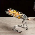 Decorazione originale con frutta fresca in bottiglia, supportata da una catena metallica, perfetta come oggetto decorativo scientifico o da tavola.