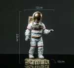 Modello di astronauta in miniatura con tuta spaziale e casco dorato, altezza circa 22 cm, perfetto come decorazione scientifica o oggetto da collezione.