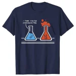 T-shirt blu con disegno di due provette con facce animate, una triste e una felice, con il testo "I think you're overreacting". Design umoristico e originale per appassionati di scienza.