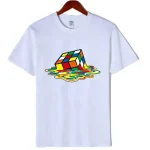 Maglietta bianca con stampa di un Cubo di Rubik che sembra galleggiare su una superficie colorata, perfetta per appassionati di enigmistica e cultura pop.