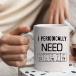 Tazza con scritta "I periodicamente ho bisogno" e simboli degli elementi chimici, perfetta come decorazione scientifica o regalo per appassionati di chimica.