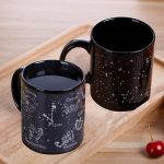 Due tazze nere con motivi zodiacali e stelle bianche, ideali come decorazioni o regali a tema astronomico. Perfette per gli amanti dell'astronomia e delle costellazioni.