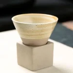 Vaso in ceramica con finitura naturale, ideale come decorazione scientifica o da collezione, posizionato su una base quadrata in cemento.