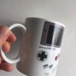 Tazza decorativa a forma di Nintendo Game Boy, perfetta per gli appassionati di videogiochi e collezionisti, con dettagli realistici e design vintage.