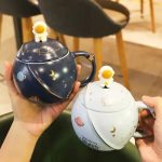 Tazza decorativa a forma di pianeta con dettagli di stelle e lune, disponibile in vari colori, perfetta per gli amanti dell'astronomia e della decorazione scientifica.