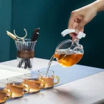 Persona versa tè in tazze di vetro con infusore, creando un'atmosfera di laboratorio scientifico elegante e funzionale. Perfetto per decorazioni e oggetti scientifici.