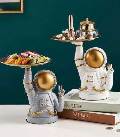 Decorazioni da tavolo a forma di astronauta con vassoi, perfette per ambienti scientifici o tematici, in stile moderno e originale, con dettagli dorati e bianchi.