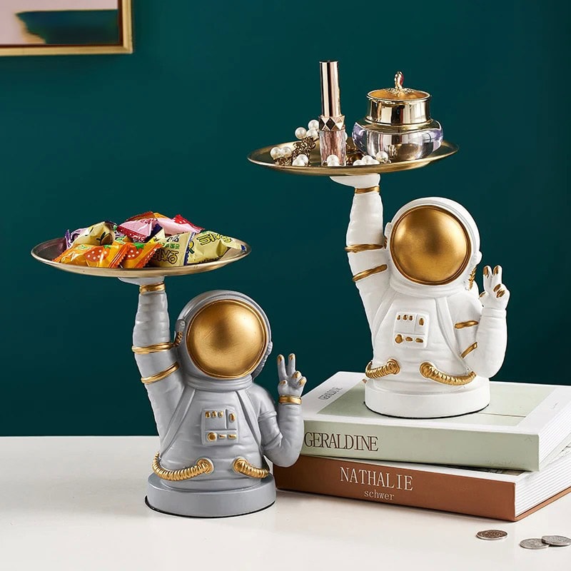 Oggetti scientifici decorativi astronauta con vassoi Decorazioni da tavolo a forma di astronauta con vassoi, perfette per ambienti scientifici o tematici, in stile moderno e originale, con dettagli dorati e bianchi.