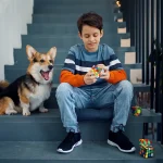 Ragazzo che gioca con un cubo di Rubik e un cane da compagnia su scale esterne, ambiente urbano, momento di divertimento e relax.