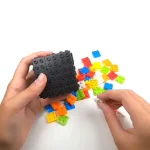 Pezzo di Lego con blocchi colorati e scatola nera, oggetto di gioco e decorazione scientifica.