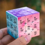 Cubi di plastica colorati con simboli e masse atomiche di elementi chimici della tavola periodica, ideali come decorazioni educative o oggetti scientifici.