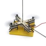 Dispositivo scientifico con piattaforma gialla, struttura in metallo e asta verticale, utilizzato per esperimenti di fisica e scienze.